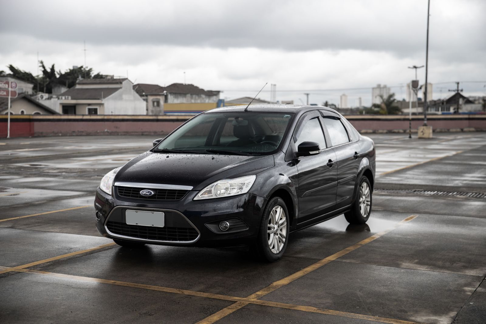 Black Ford sedan parked in a spacious São Paulo parking lot on a cloudy day.