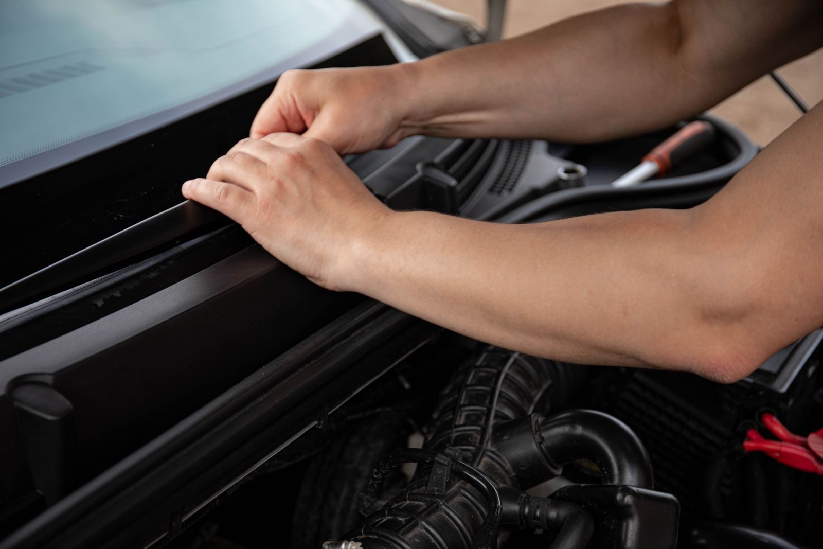 Close-up of a mechanic's hands repairing a car engine, showing detailed work.